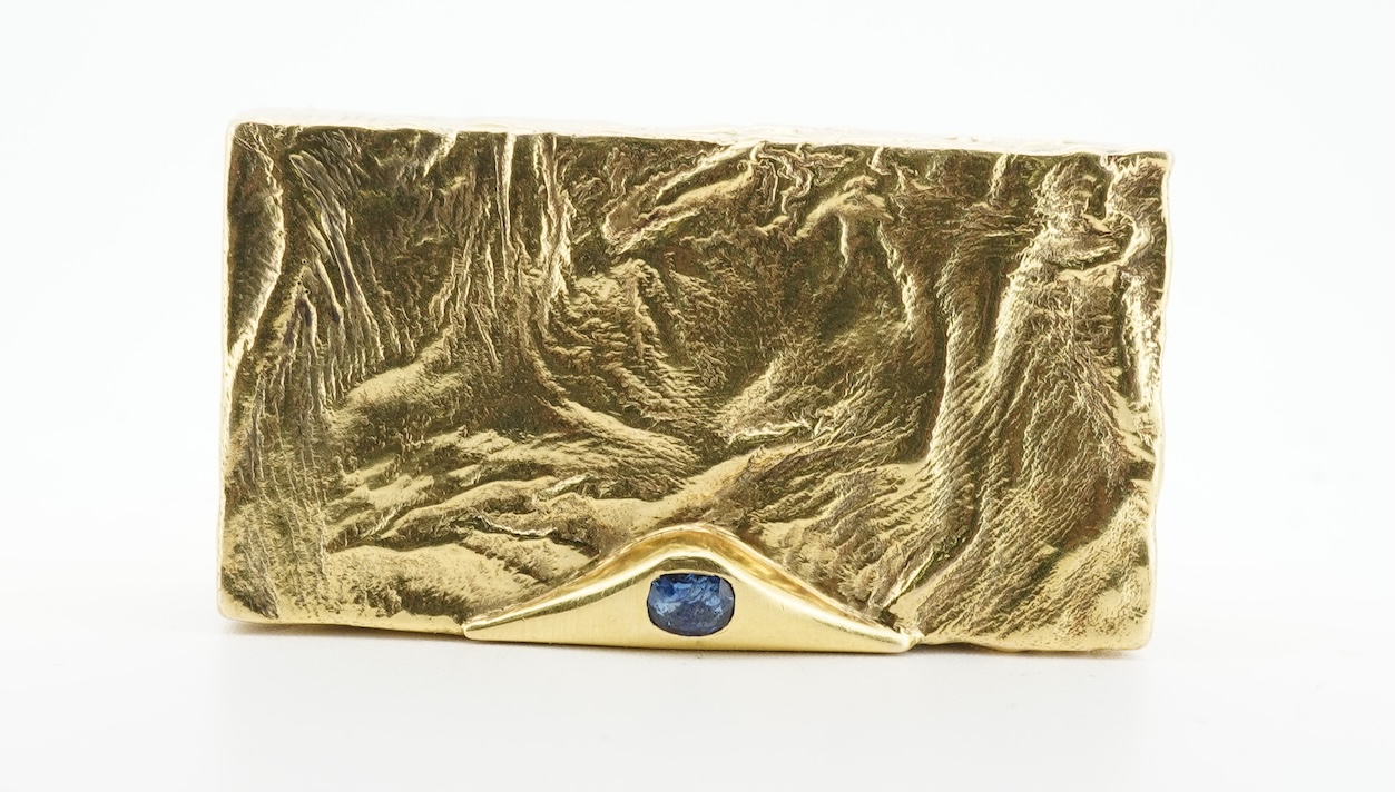 Dunhill, an attractive 9ct gold and sapphire snuffbox, circa 1973, the rectangular box of samorodok finish, the hinged lid set with a foil-backed oval sapphire, measuring approximately 5.1 x 2.7 x 1.6cm, signed Dunhill L